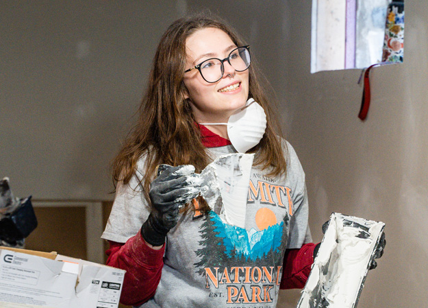 Habitat worker applying drywall mud