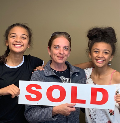 Parent with children holding a Sold sign