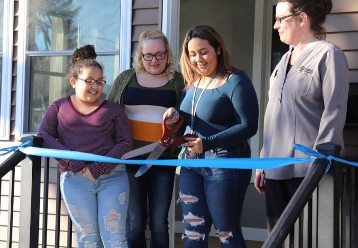 habitat home recipient cutting ribbon on new home