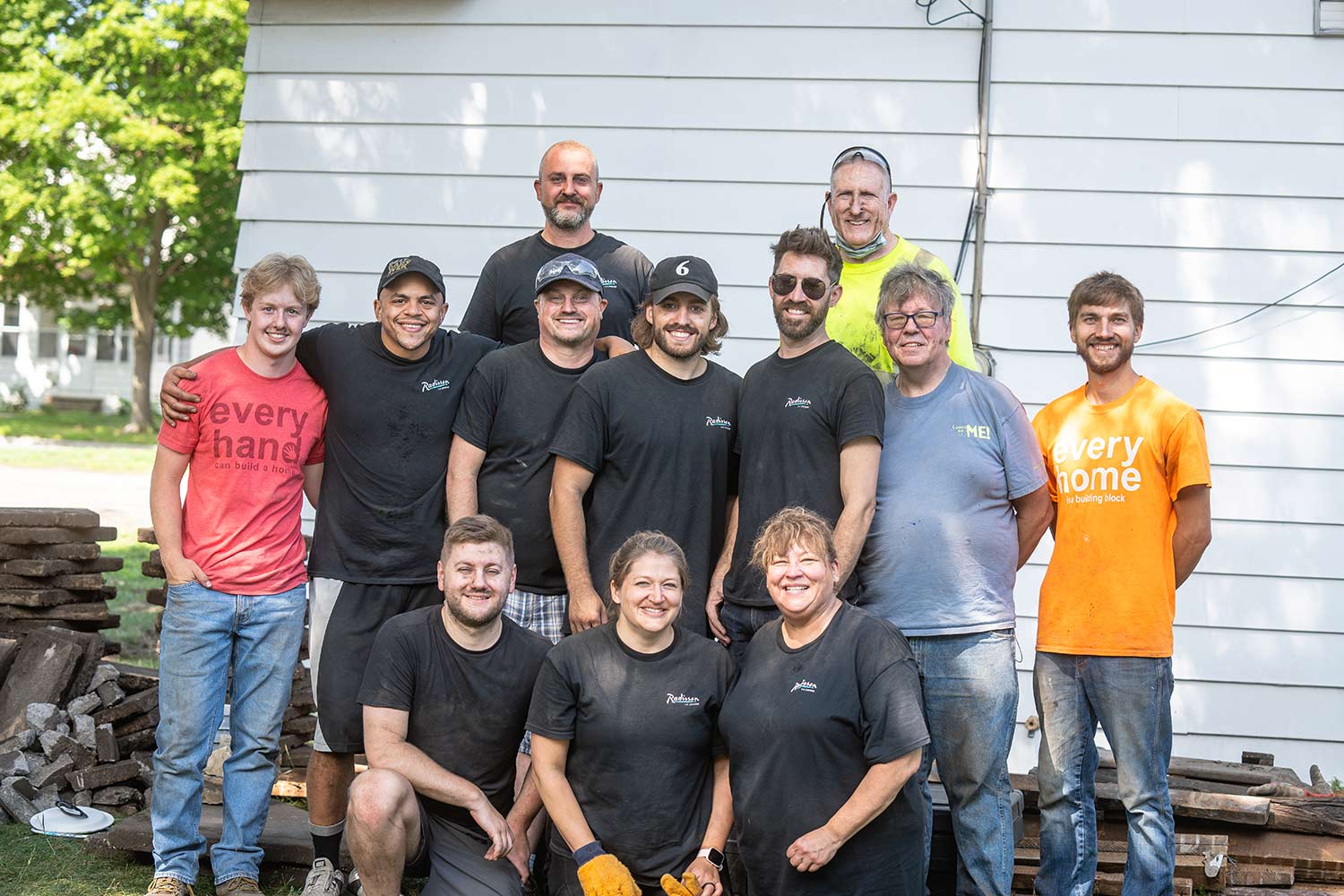 team posing for pic in front of house