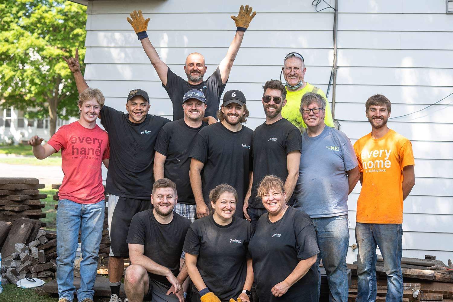 Workers and volunteers posing for pic in front of house