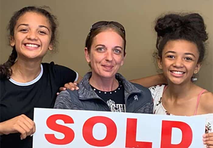 family holding sold sign