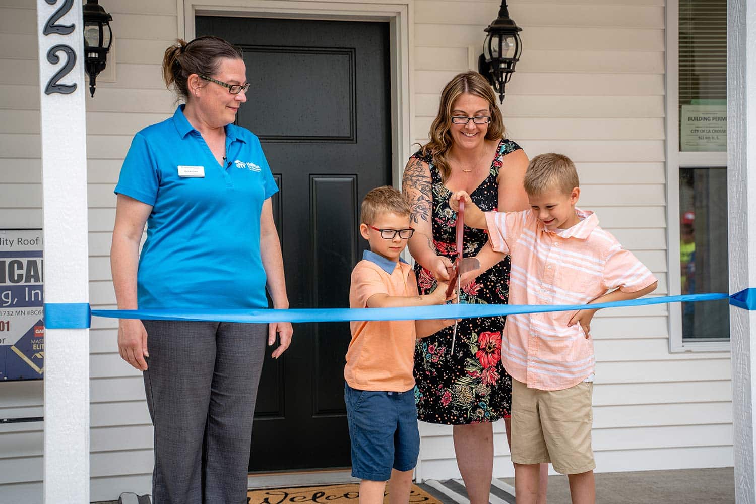 Mother and two sons cutting ribbon at dedication ceremony for the house