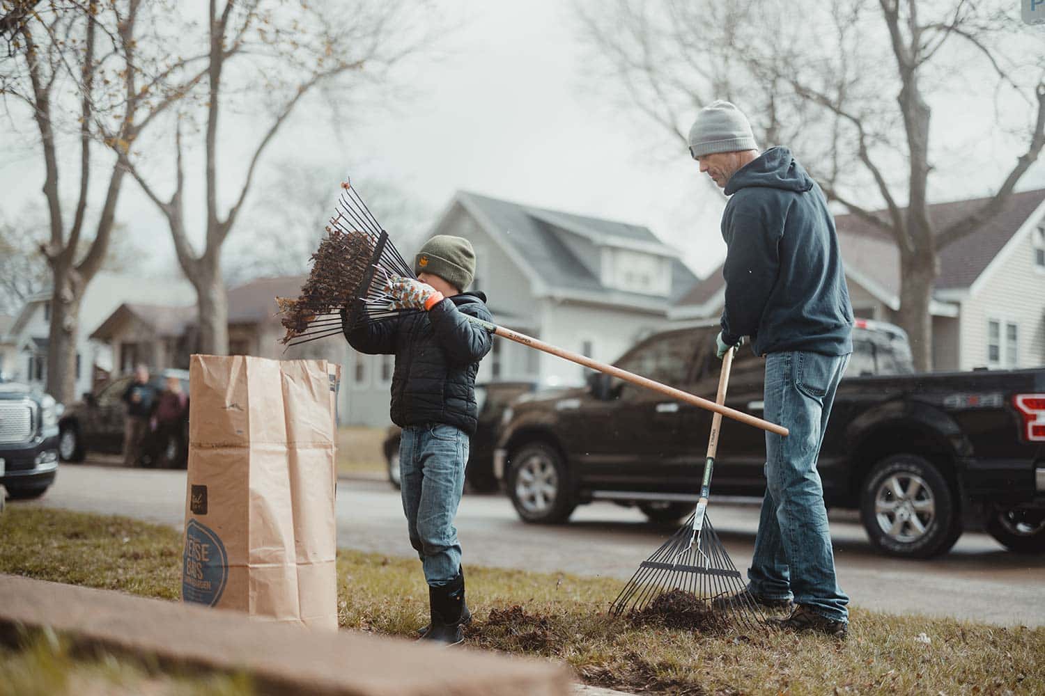 volunteers with a child raking leaves